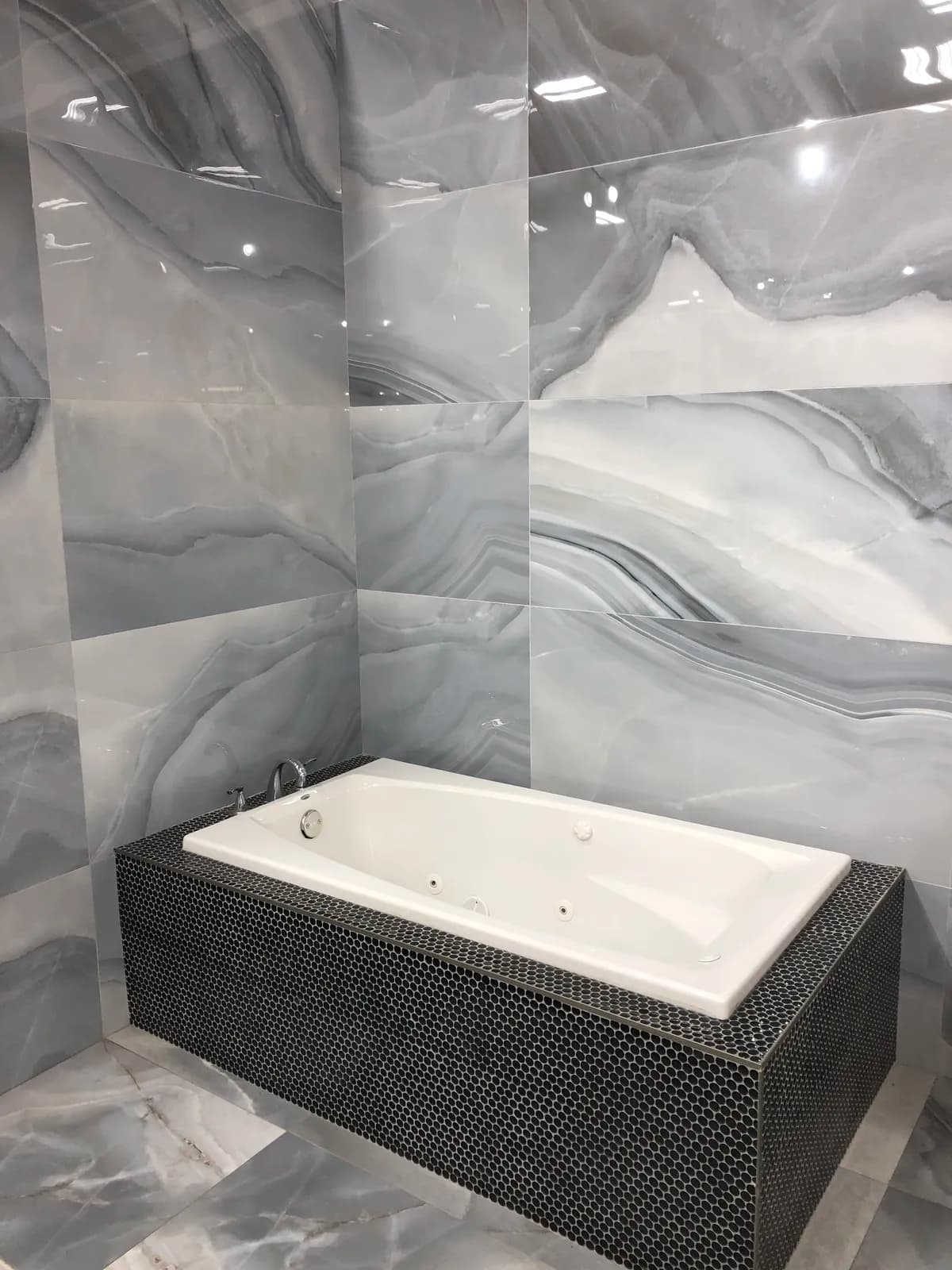 Statement Spa Bath — Dramatic agate-veined slab walls paired with a penny-round mosaic tub surround for a true spa retreat.